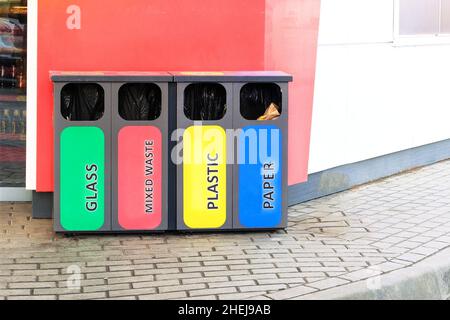 Separate garbage collection containers on gas station. Collection of plastic, paper, glass and mixed wasted for further processing. Stock Photo