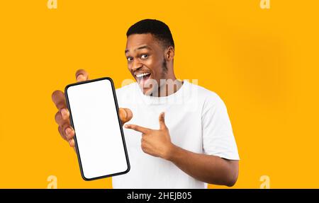 Happy handsome black man holding smartphone with empty screen Stock Photo