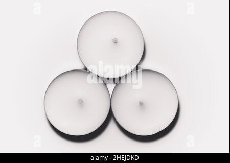 Monochrome white three tea light on white background top view close up Stock Photo