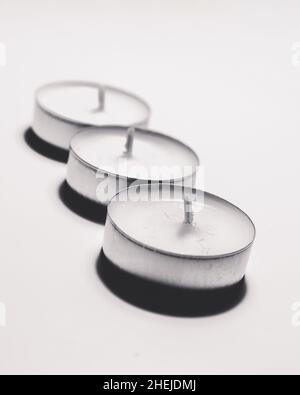 Monochrome white three tea light on white background one after another Stock Photo