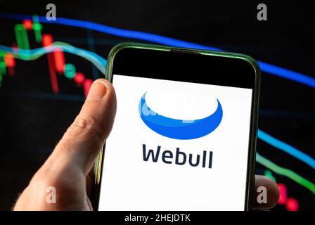 China. 09th Dec, 2021. In this photo illustration the financial trading services company Webull logo seen displayed on a smartphone with an economic stock exchange index graph in the background. (Photo by Budrul Chukrut/SOPA Images/Sipa USA) Credit: Sipa USA/Alamy Live News Stock Photo