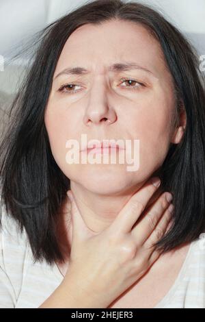 Mature woman touching her neck. Sick woman feels sore throat, cough