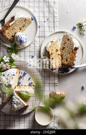 Easter composition with sliced cake, flowers and eggs on a light background with checkered tablecloth Stock Photo