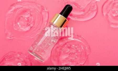 Collagen Serum or hyaluronic serum in dropper on pink color background. Skincare cosmetic product bottle for face skin on Collagen swatch. Cosmetics Stock Photo