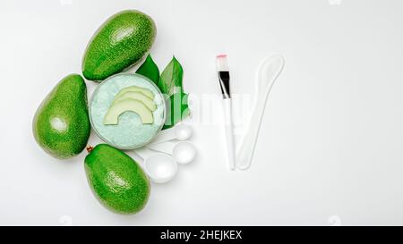 Natural cosmetics face skin care made from avocado. Avocado fruit face mask. Set of tools for making home cosmetics. Flat lay on white background Long Stock Photo
