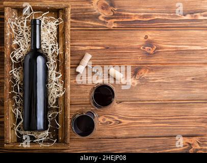Red Wine composition on brown wooden table. Top view. Red wine bottle corkscrew corks wine glasses on wooden table with copy space. Stock Photo