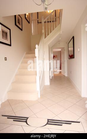 Cream tiled floor and staircase in the hallway of a new modern detached house Stock Photo