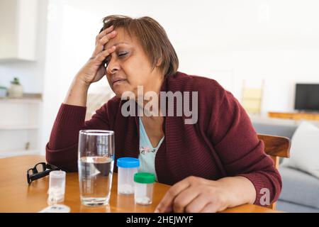 African american senior woman suffering from headache while sitting at table Stock Photo