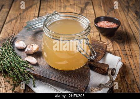 Bone broth for chicken soup in a glass jar. Wooden background. Top view Stock Photo