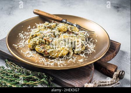 Cooked Gnocchi potato pasta with spinach and parma ham on plate. White background. Top view Stock Photo