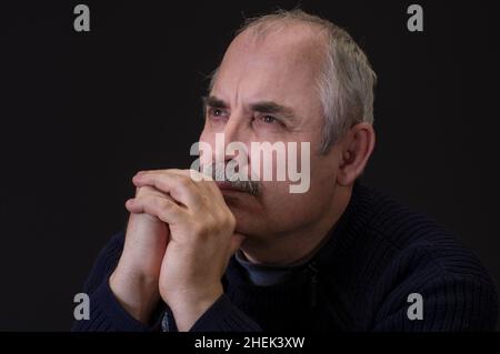Nice portrait of of a thoughtful Caucasian mature man against black background Stock Photo