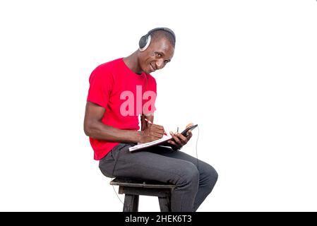handsome adult man listening to music with headphones and taking notes using a cellphone. Stock Photo