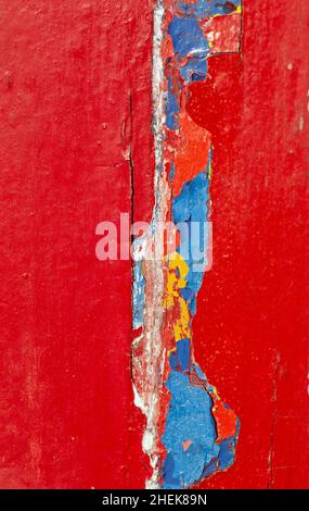 Peeling paint on a vibrant red painted timber panel Stock Photo