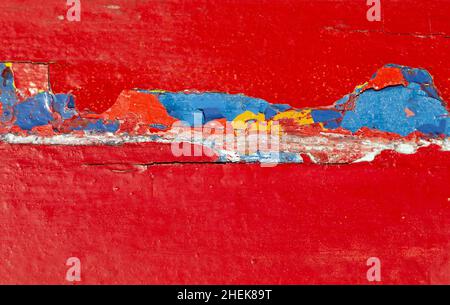 Peeling paint on a vibrant red painted timber panel Stock Photo