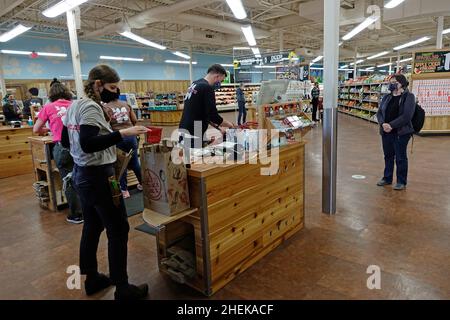 employee bagging groceries at Trader Joes during Covid 19 in Foxborough MA Stock Photo