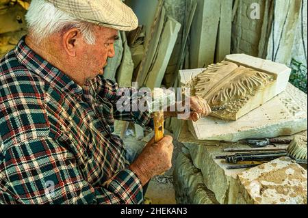 Stonemason at work on a stone sculpture. Creation of handcrafted decorations carved in the Maiella stone. Lettomanoppello, Pescara province, Abruzzo, Stock Photo