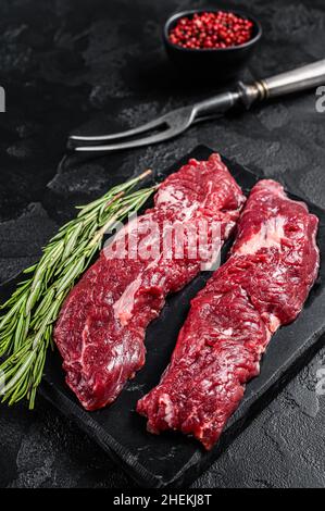 Raw Machete steak or hanging tender cut with herbs. Black background. Top view Stock Photo