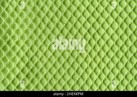 Green mesh over cotton jersey macro texture. Background of light green knitted textile with mesh for casual and sportswear. Modern clothing fabric. Stock Photo