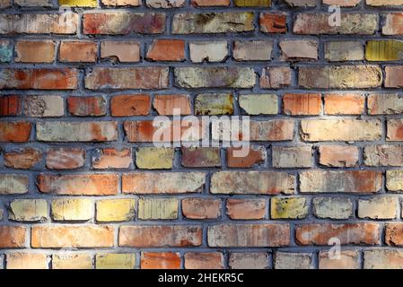 Abstract background. Texture of an old brick wall close-up. Orange, red, yellow bricks. Stock Photo