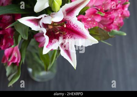 Fresh lily and pink alstroemeria flower bouquet on a dark wood background with copy space Stock Photo