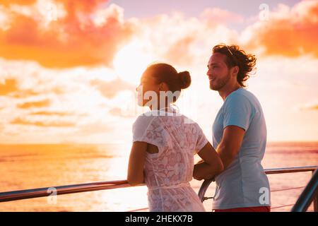 Sunset cruise romantic couple watching view from boat deck on travel vacation. Silhouette of man and woman tourists relaxing on outdoor balcony of Stock Photo