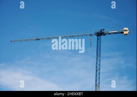 Construction cranes seen against a blue sky with clouds Stock Photo