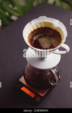 Brewing ground coffee through paper filters into a glass coffee pot. Standing on electronic scales Stock Photo