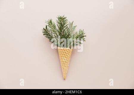 Edible waffle cone with evergreen branches and waffle cone in the middle on cream color background. Concept Christmas greeting card. Stock Photo