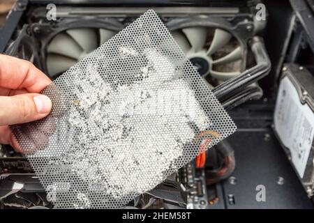 Dirty computer case. A layer of dust on the system unit. Time to clear your computer of dust. Dusty mesh from the computer in hand Stock Photo