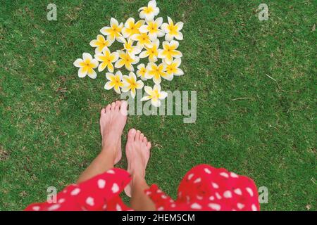 Flower petals romantic getaway Hawaii vacation travel. Woman POV walking barefoot on summer grass. Tropical flowers laid on floor for outdoor wedding Stock Photo