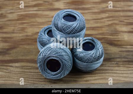 Detail of some balls of dark gray thread with ten grams of quality Perlé thread number 8 on an old wood Stock Photo