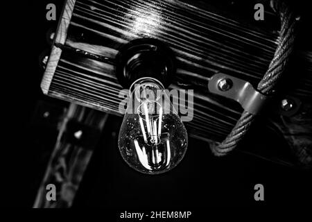 Beautiful lighting vintage style lamp mounted on a wooden ceiling. Black and white image. Selected focus. Stock Photo