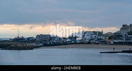 Lyme Regis, Dorset. 11th January 2022. UK Weather: The dull and dreary weather of the last few days shows some signs of clearing at the seaside resort of Lyme Regis as fog lifts over the roof tops. Credit: Celia McMahon/Alamy Live News