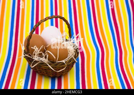 General shot of a small basket in which there are some brown and white eggs on a colored background with copy space Stock Photo