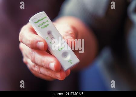 Hands of a woman holding a Rapid Response Covid-19 antigen test with a negative result. Stock Photo