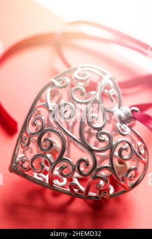 Saint Valentine day greeting card, beautiful silver heart with ribbon on red background with shadows Stock Photo