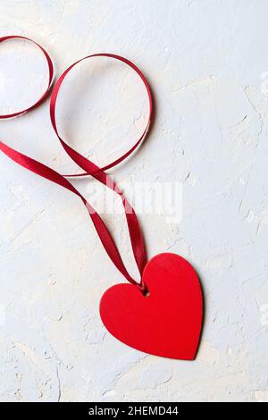 Red painted heart with ribbon on grey textured background, Saint Valentine day minimalistic card Stock Photo