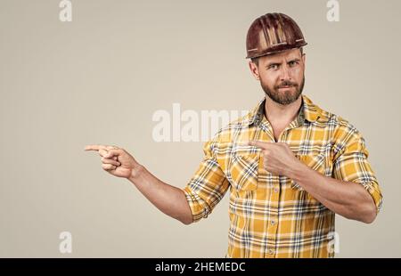 look over there. mature builder in shirt. unshaven man on construction site. handsome building worker in hard hat. labor day. guy wear safety helmet Stock Photo