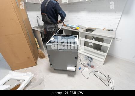 Installation hoses for dishwasher machine domestic connection plumbing pipes in kitchen Stock Photo
