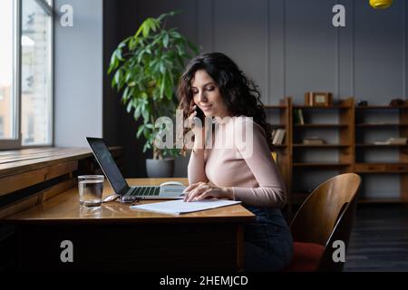 Young european business woman discussing contract details with business partner via mobile phone Stock Photo