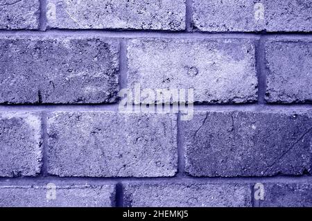 Old authentic brick wall with antique brickwork. Uneven defective brickwork. Tinted in a Very peri for the designer. Stock Photo