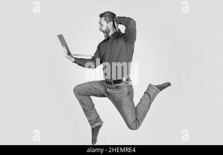 surprised energetic man jumping while working online on laptop hurry up for shopping, surprise. Stock Photo