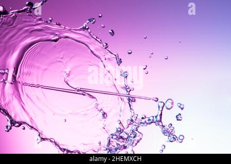 Clear water liquid splash on a purple color background Stock Photo