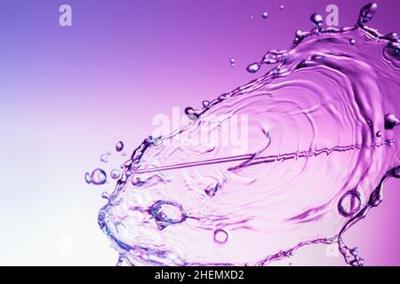 Clear water liquid splash on a purple color background Stock Photo