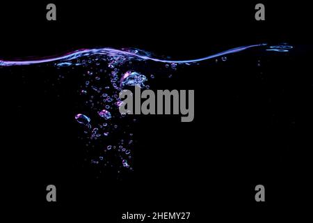 Clear water surface with ripple and bubbles in red and blue light on a black nature background Stock Photo