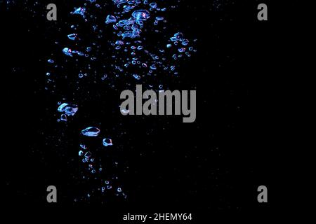 A bubble splash in transparent clear water liquid in red and blue light on a black nature background Stock Photo