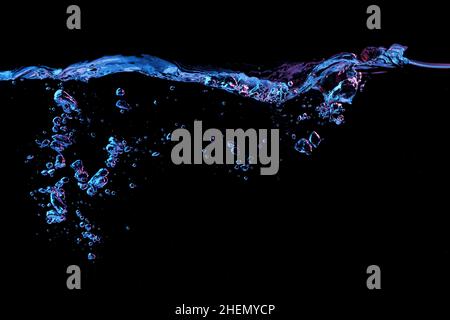Clear water surface with ripple and bubbles in red and blue light on a black nature background Stock Photo