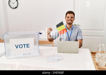 Young hispanic man smiling confident holding belgium flag working at electoral college Stock Photo