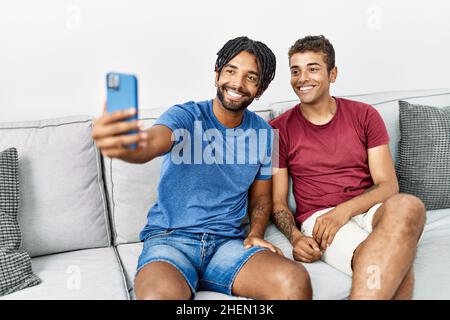 Two men friends make selfie by the smartphone sitting on sofa at home Stock Photo