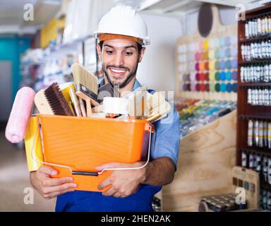 Workman holding basket with picked tools in paint store Stock Photo
